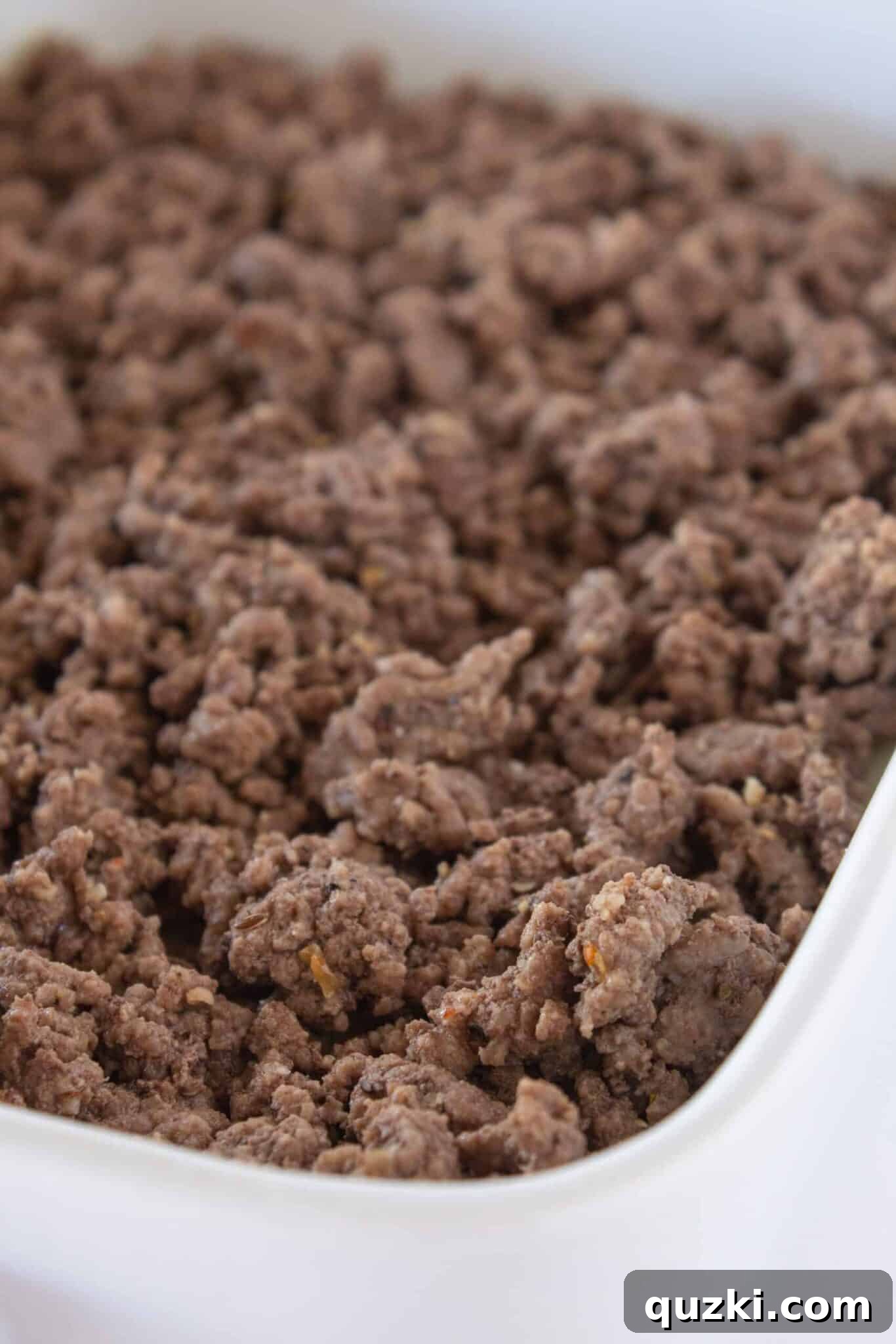 Adding cheese and cooked ground beef to the Patty Melt Casserole layers.