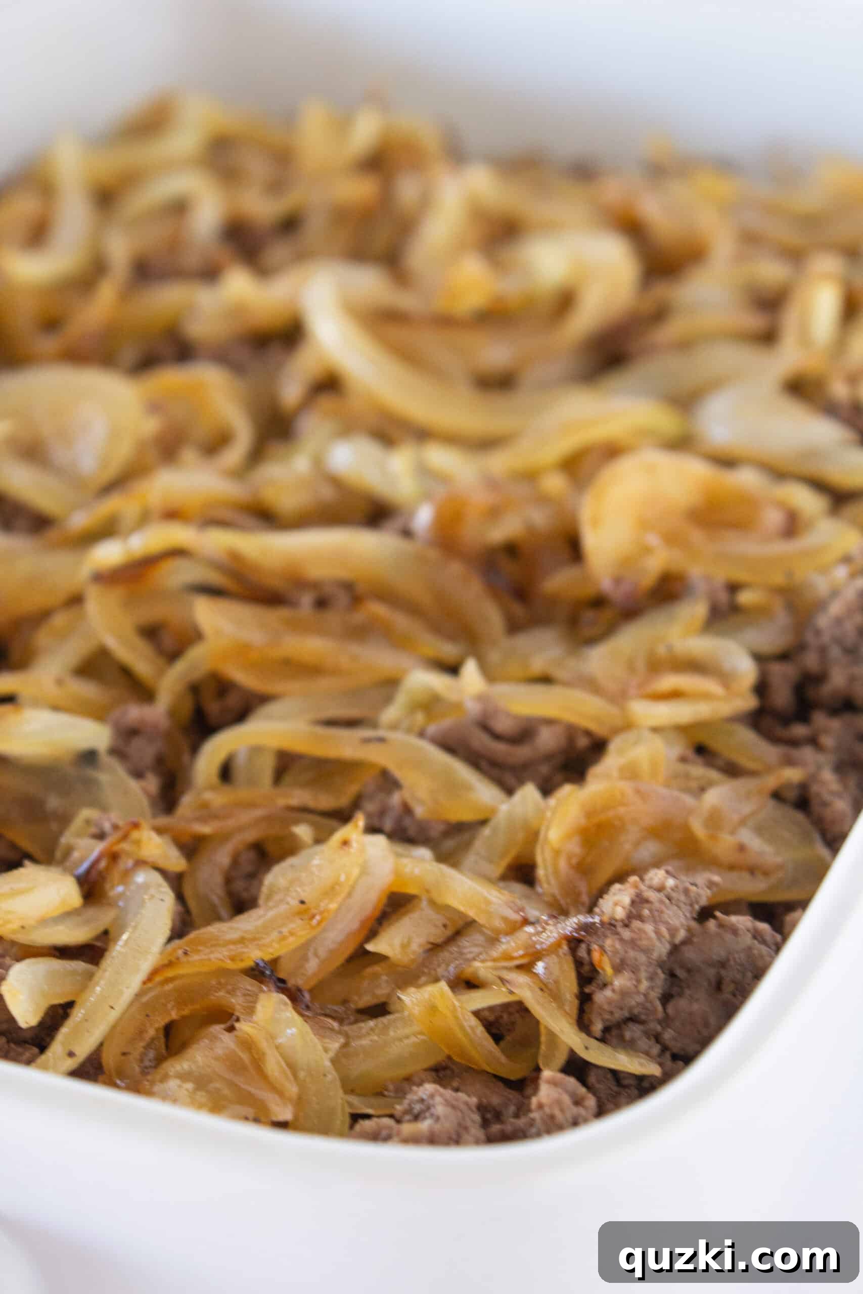 Classic Patty Melt Casserole Recipe featured by top US food blogger, Practically Homemade, showing sauce and onion layers.