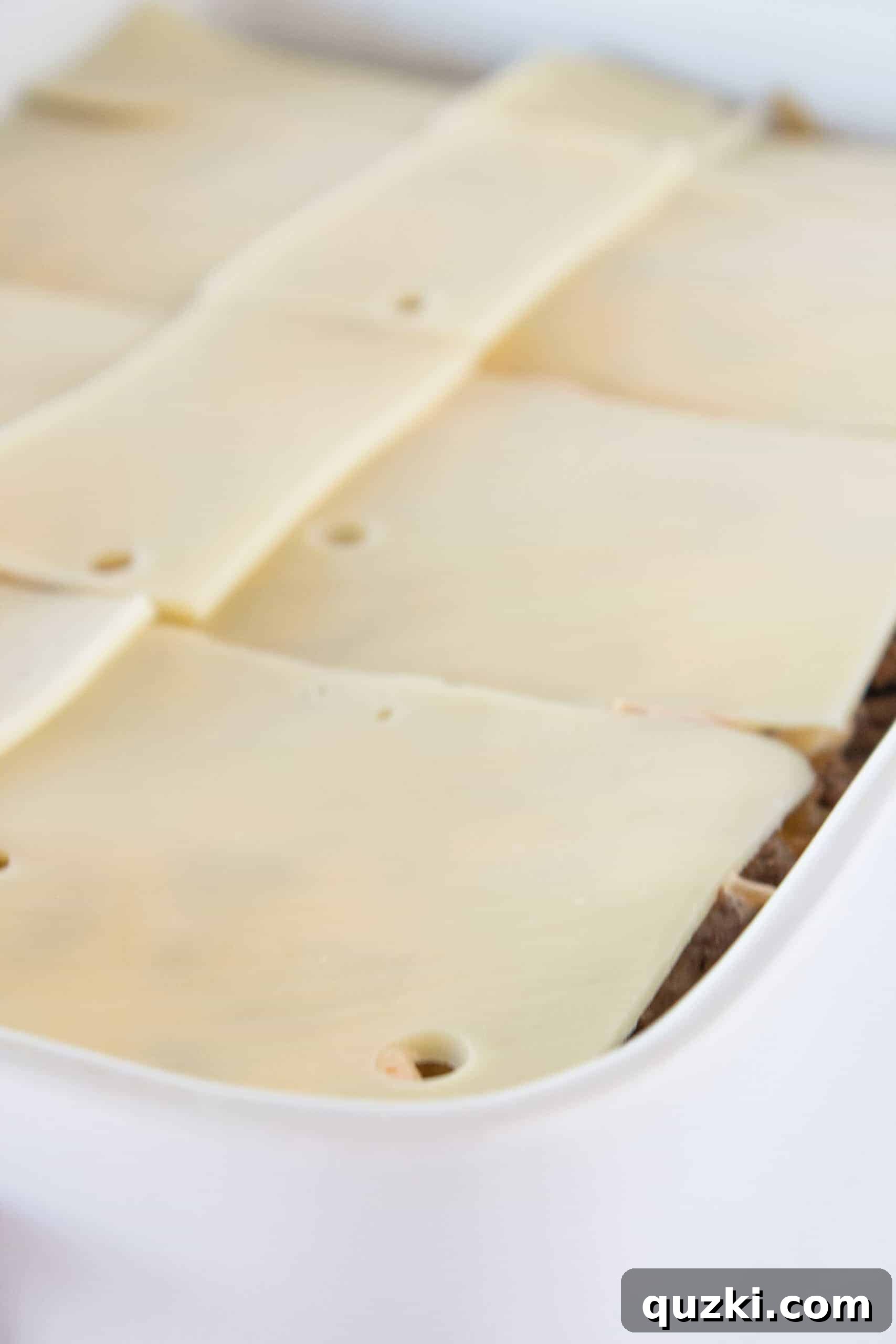 Classic Patty Melt Casserole Recipe featured by top US food blogger, Practically Homemade, showing final layers before baking.