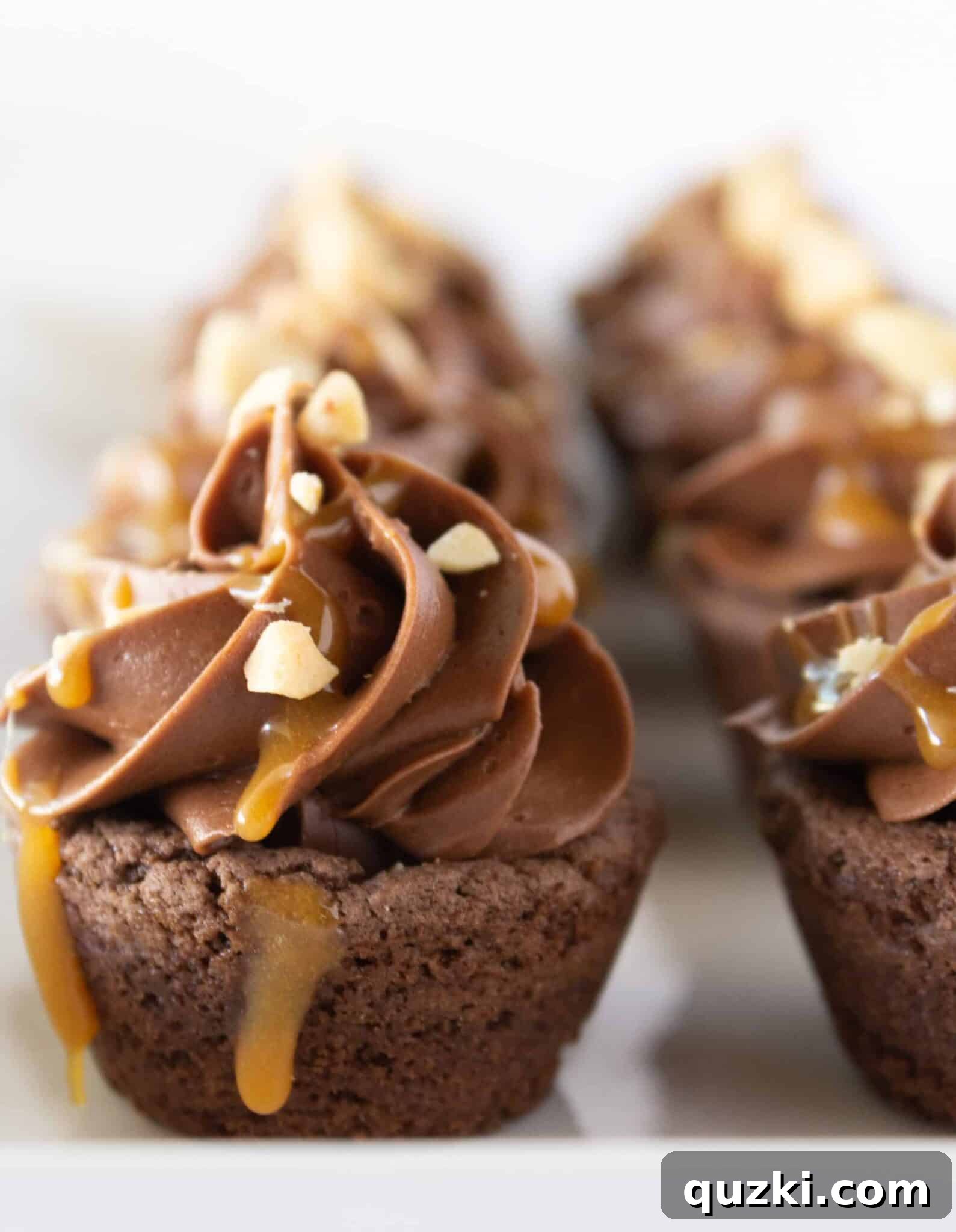 Ultimate Snickers Cookie Cups 2 Easy Snickers Cookie Cups on a white tray with a caramel drizzle, ready to be served.