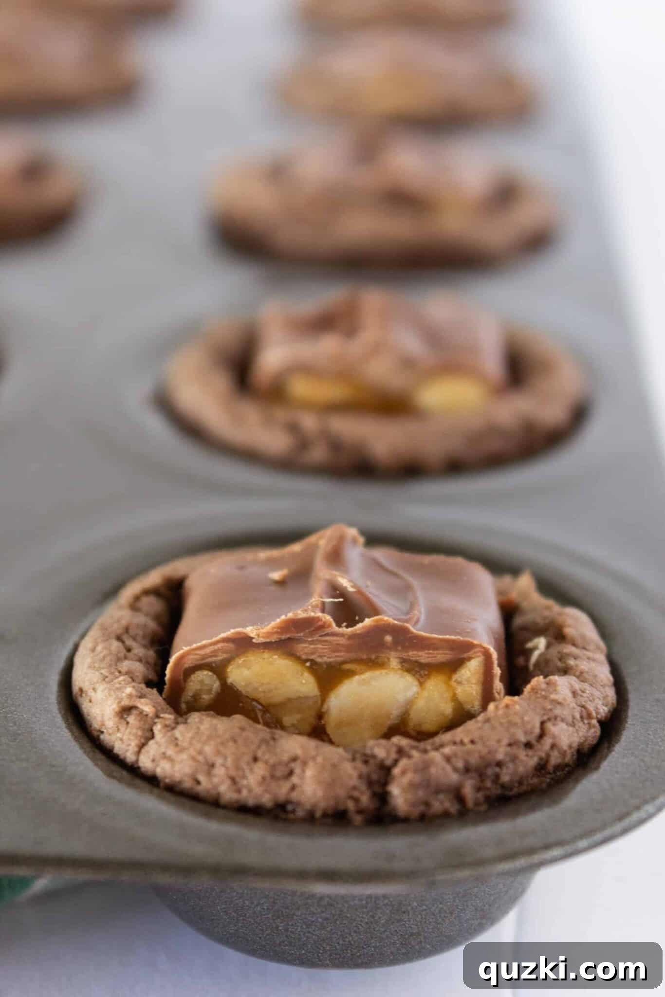 Ultimate Snickers Cookie Cups 7 Placing a piece of Snickers candy into the center of each warm chocolate cookie cup.