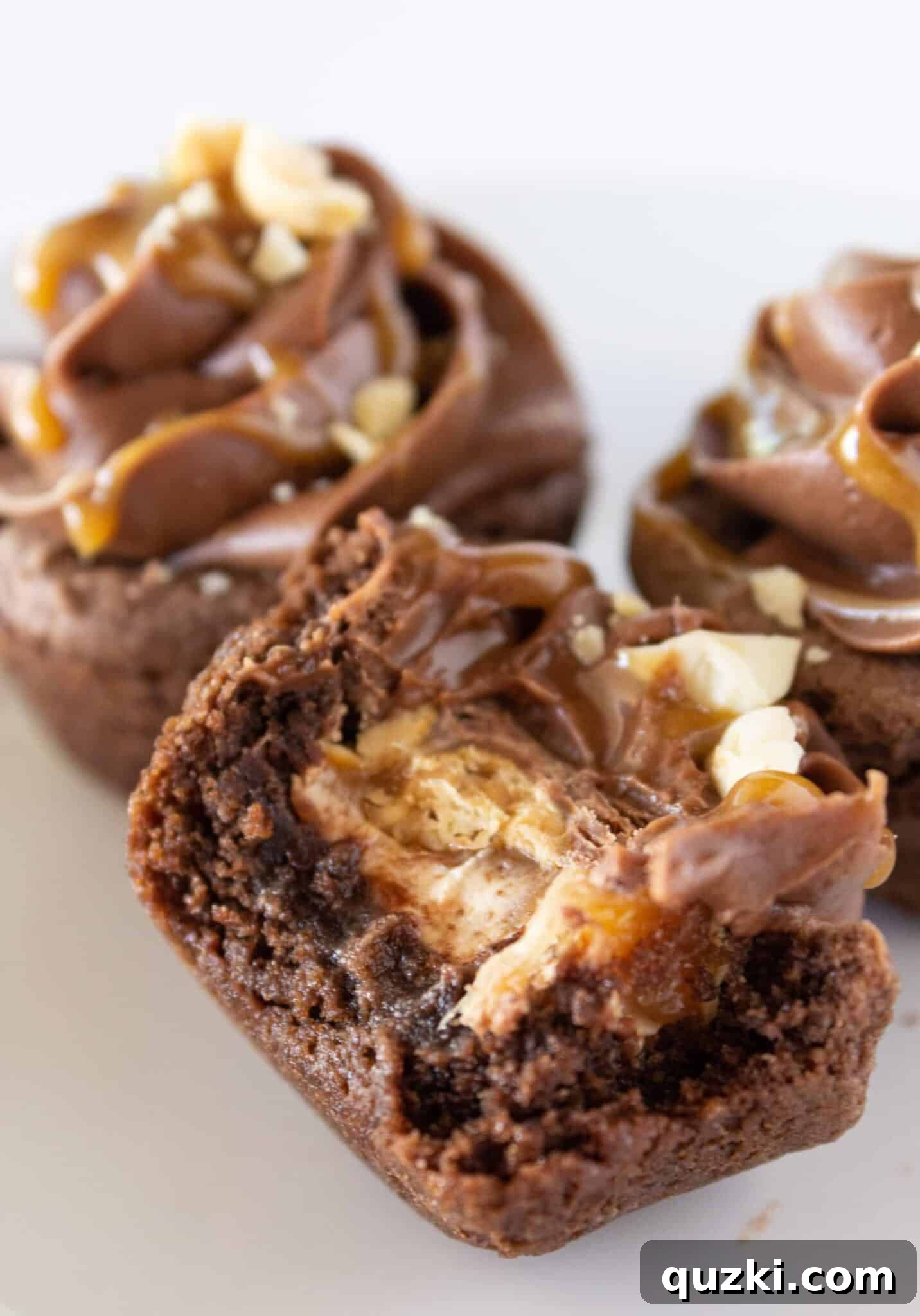 Ultimate Snickers Cookie Cups 10 A Snickers Cookie Cup with a bite taken, revealing the luscious melted Snickers candy inside.