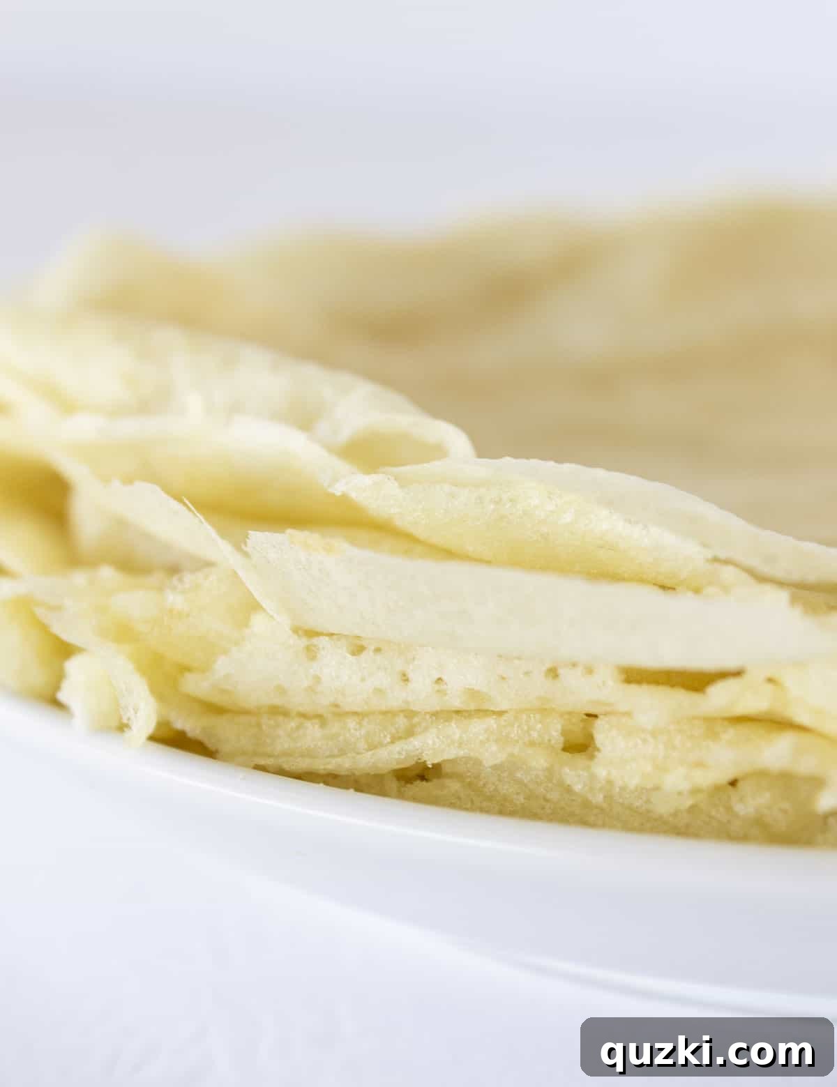 Pancake mix crepes stacked on a white plate, ready to be served.