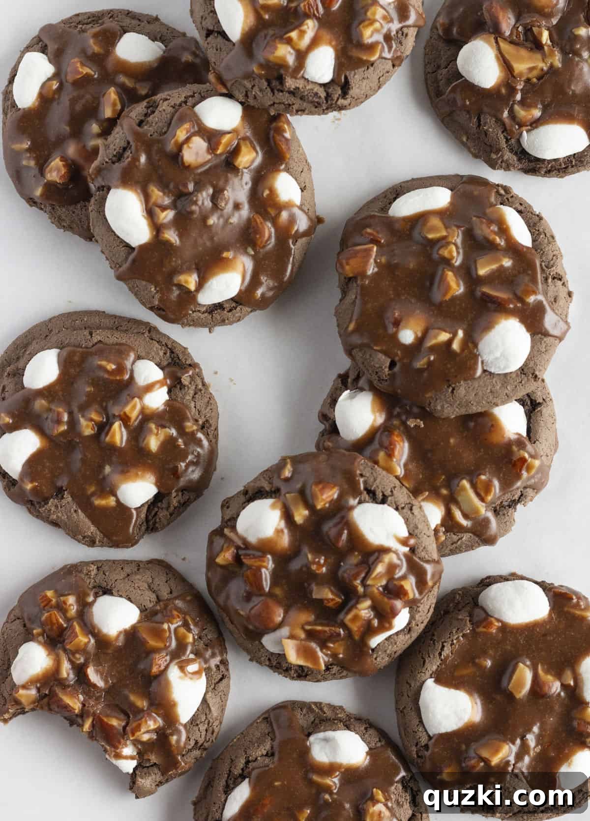 A dozen delectable rocky road cookies arranged beautifully on a pristine white tray, showcasing their rich chocolate color, fluffy white marshmallows, and crunchy almond topping.