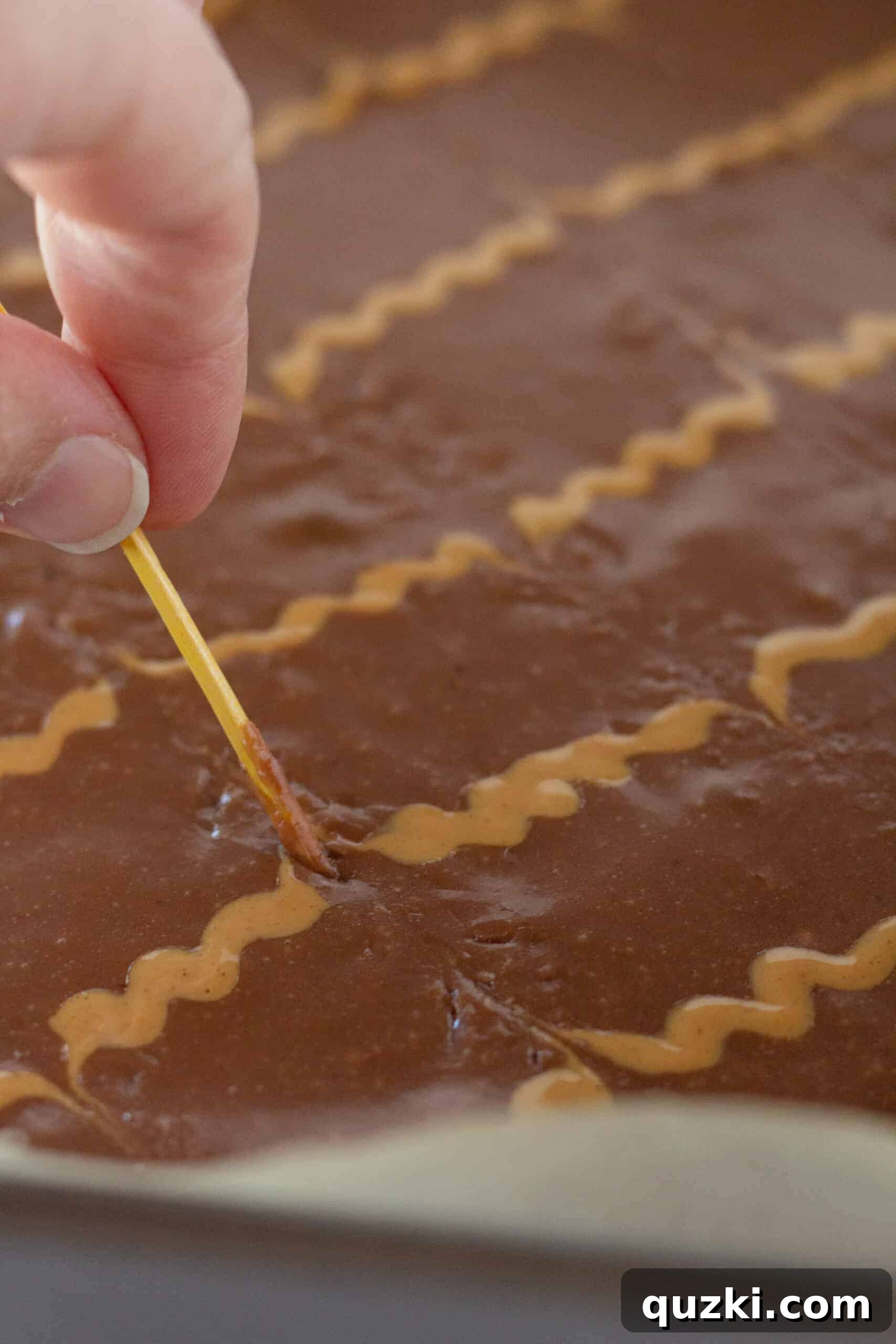 Applying the chocolate frosting evenly over the cooled brownies.