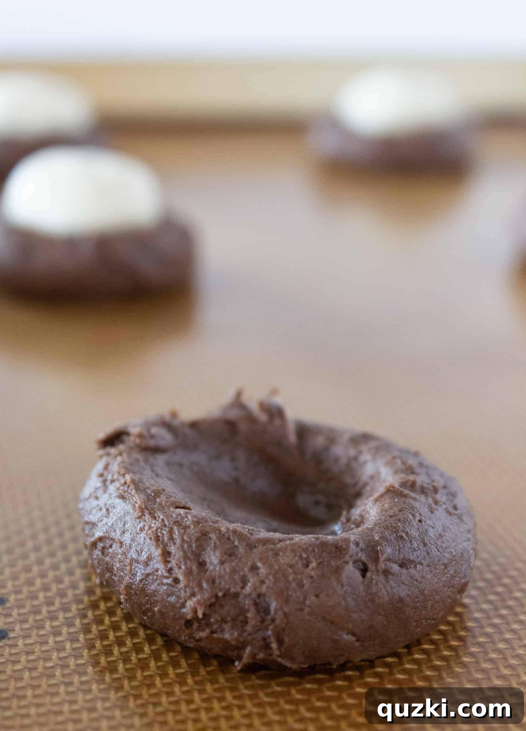 Cake Mix Chocolate Cheesecake Cookies 7 The process of assembling chocolate cheesecake cookies, showing a cheesecake ball placed into a divot in chocolate cookie dough.
