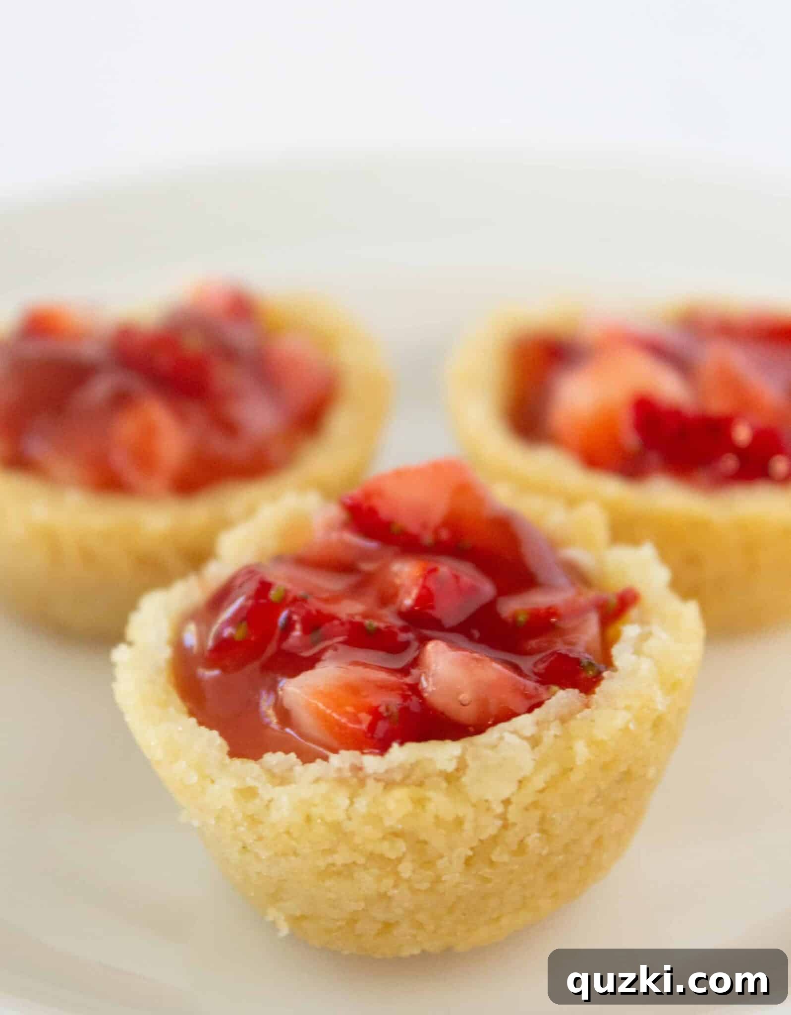 Decadent Strawberry Cream Cheese Pastries 2 Three perfectly formed Strawberry Cream Cheese Pastry Bites garnished with fresh mint on a white plate, highlighting their vibrant colors and appealing texture.