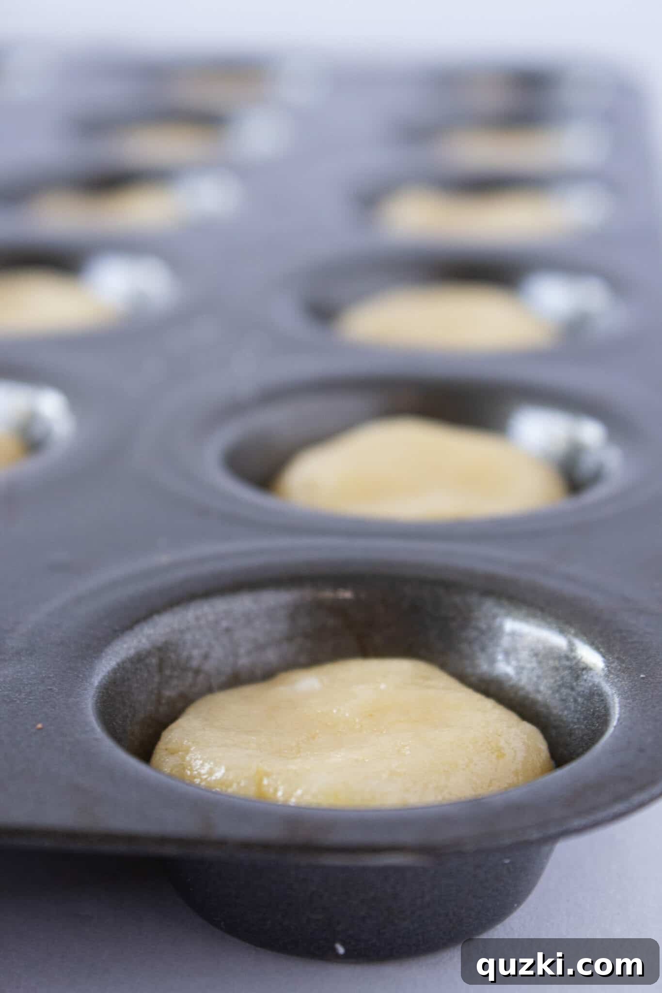 Decadent Strawberry Cream Cheese Pastries 5 Scooping sugar cookie dough into a mini muffin pan to form the base of the pastry bites.