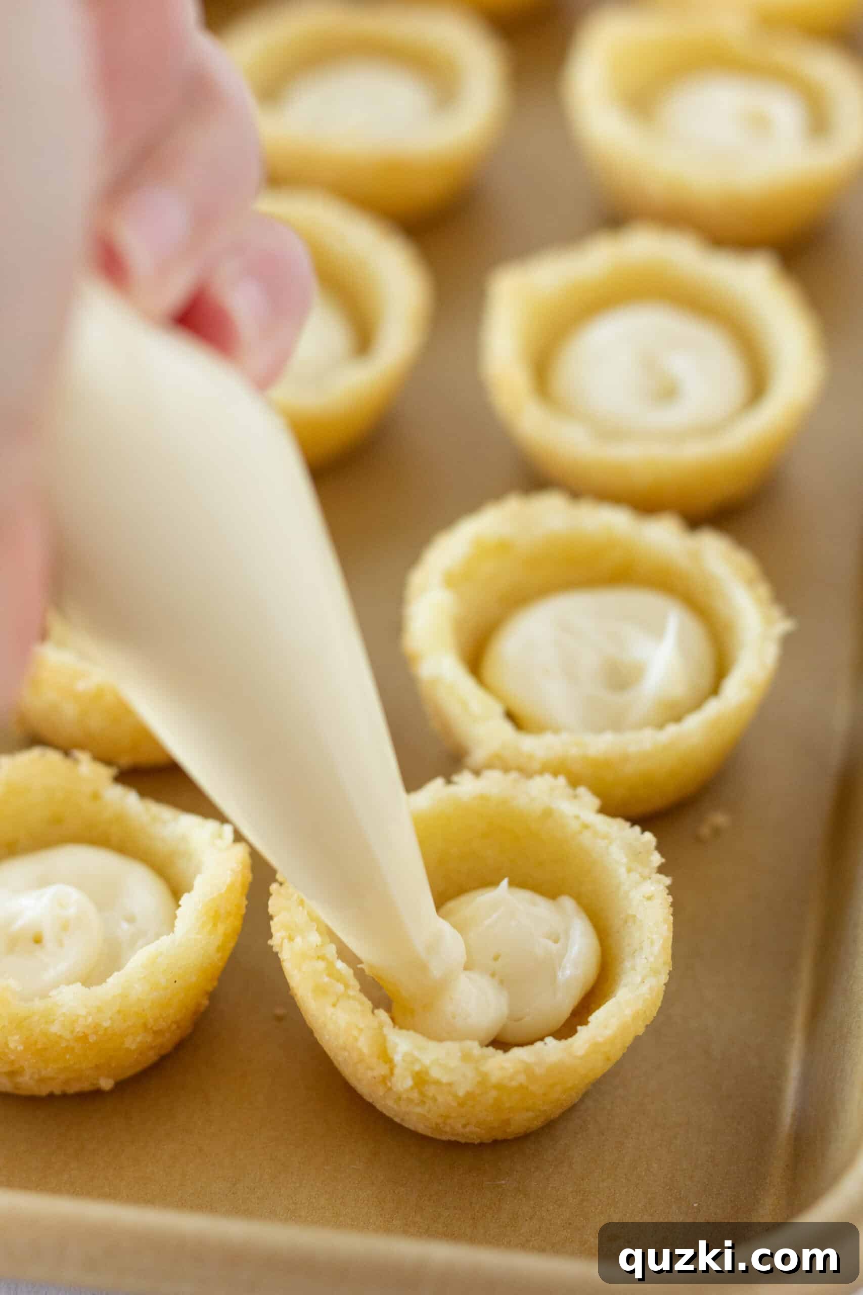 Decadent Strawberry Cream Cheese Pastries 10 Piping cream cheese filling into the sugar cookie cups, creating a smooth layer.