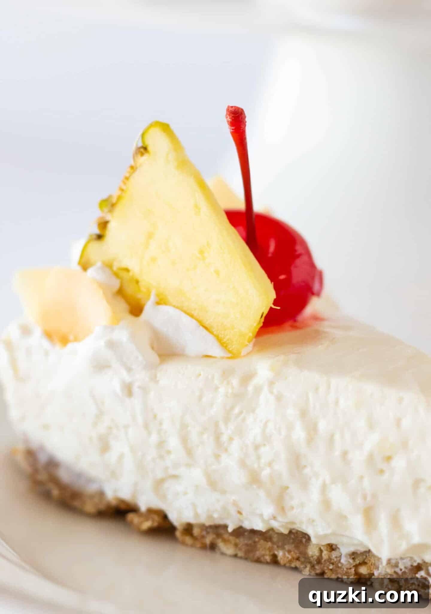 Island Escape No-Bake Cheesecake 11 A perfectly sliced portion of the no-bake Pina Colada cheesecake rests on a simple white plate, ready for serving.