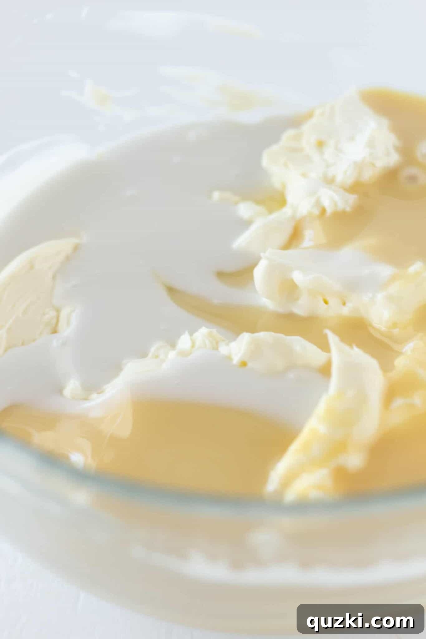 Island Escape No-Bake Cheesecake 5 Cream cheese and sweetened condensed milk being whipped together in a bowl, forming the smooth base for the no-bake Pina Colada cheesecake filling.