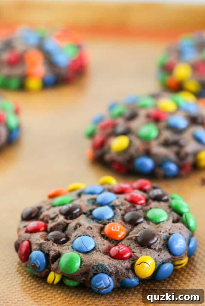 Ultimate Chocolate M and Ms Cookie Treat 7 Freshly baked Chocolate M&M cookies, made with a cake mix, showcasing their vibrant candy coating and perfectly fudgy appearance, cooling on a baking sheet.