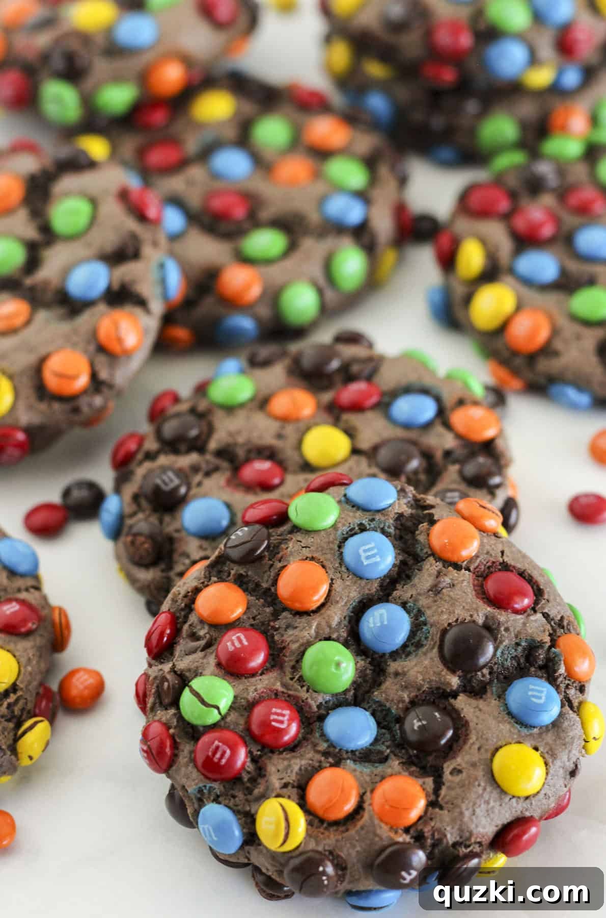 Ultimate Chocolate M and Ms Cookie Treat 8 A close-up of several simple chocolate cake mix cookies, rolled in mini M&M's and baked to golden perfection, scattered on a surface, highlighting their colorful appeal.
