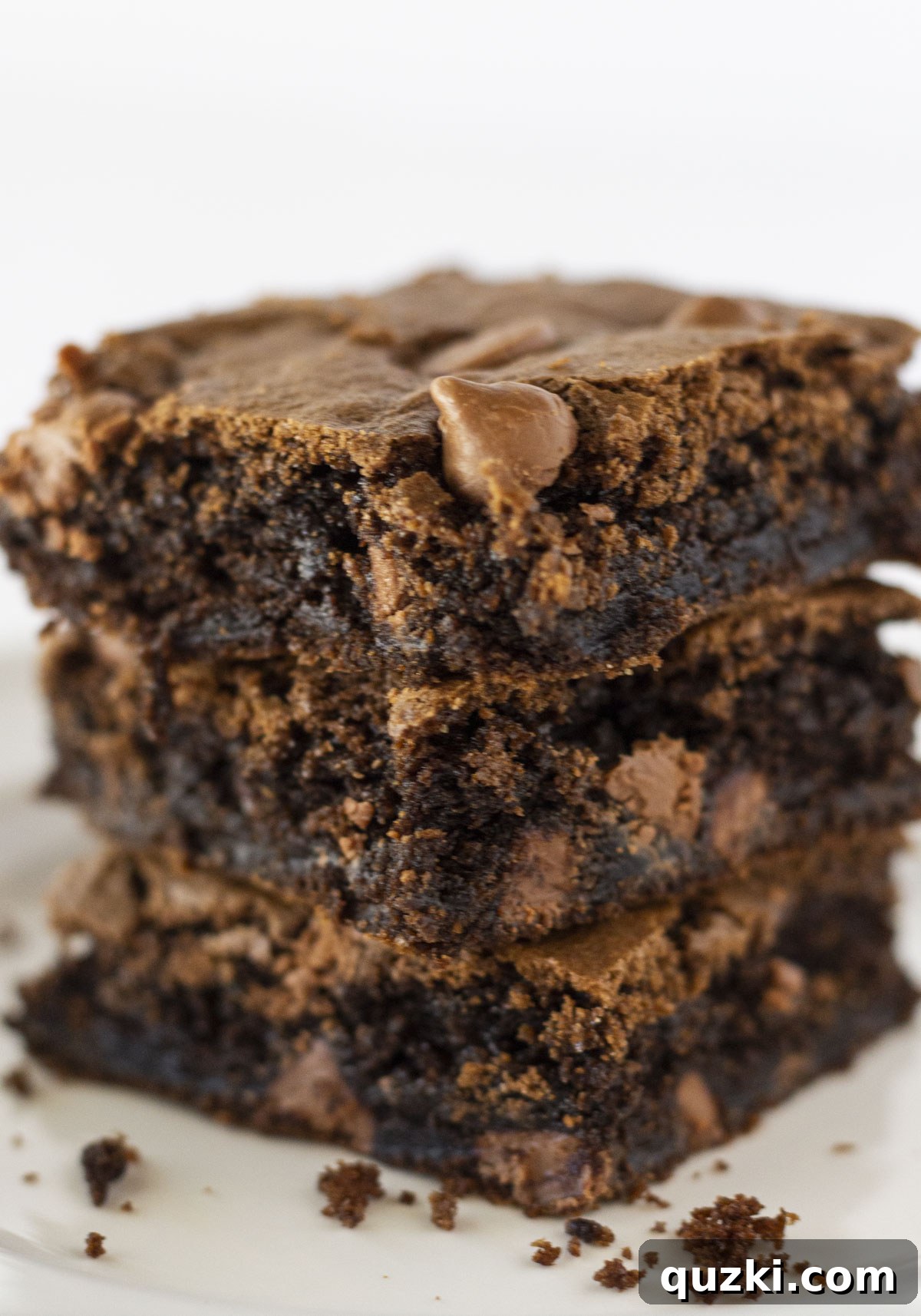 Fudgy Delights from a Cake Mix 6 A beautifully stacked trio of fudgy cake mix brownies, adorned with scattered chocolate crumbs, highlighting their rich, dark appeal.