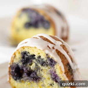 A beautifully baked Blueberry Bundt Cake with a luscious glaze, garnished with fresh blueberries, ready to be sliced and served.