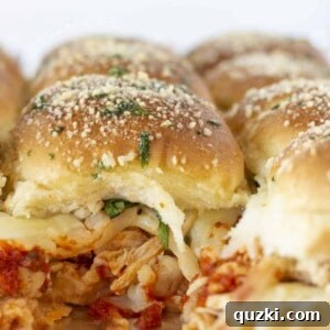 Looking at the inside of baked Chicken Parmesan Sliders, showing melted cheese and tender chicken.