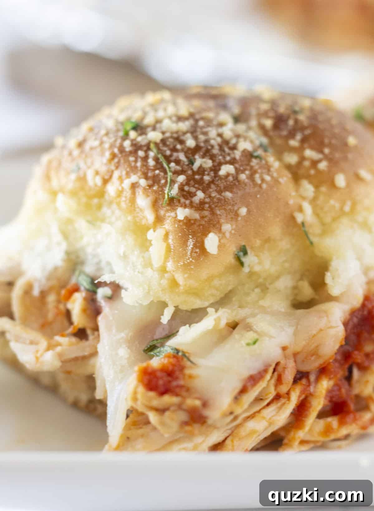 Quick Chicken Sliders 7 A single chicken parm slider presented on a white plate, garnished with fresh basil, ready for enjoyment.