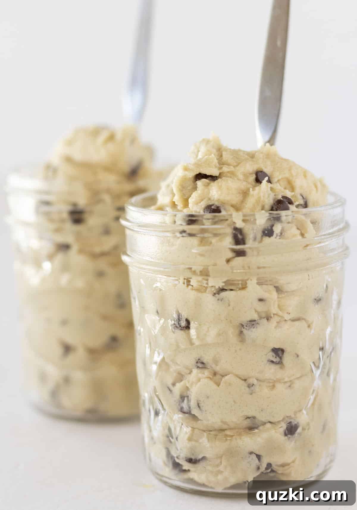 Two small mason jars filled with creamy, delicious edible eggless chocolate chip cookie dough, ready to be enjoyed.