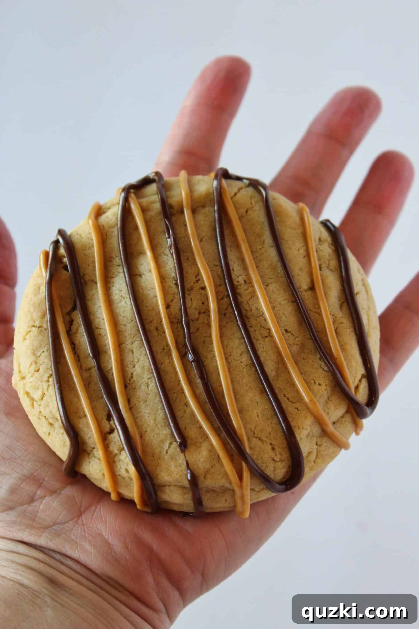 Ultimate Reese's Peanut Butter Cup Cookies 15 A hand holding a massive, freshly baked Reese's Peanut Butter Cup Stuffed Cookie, highlighting its impressive size