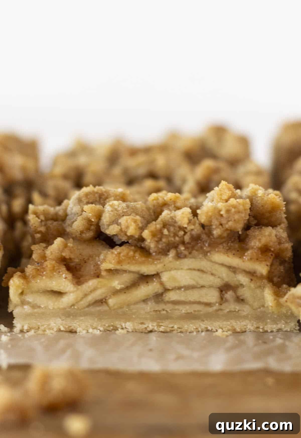 Simply Delicious Dutch Apple Pie Bars 2 A closeup of golden-brown Dutch apple pie bars, freshly baked and being skillfully cut into neat squares on a rustic wooden cutting board.