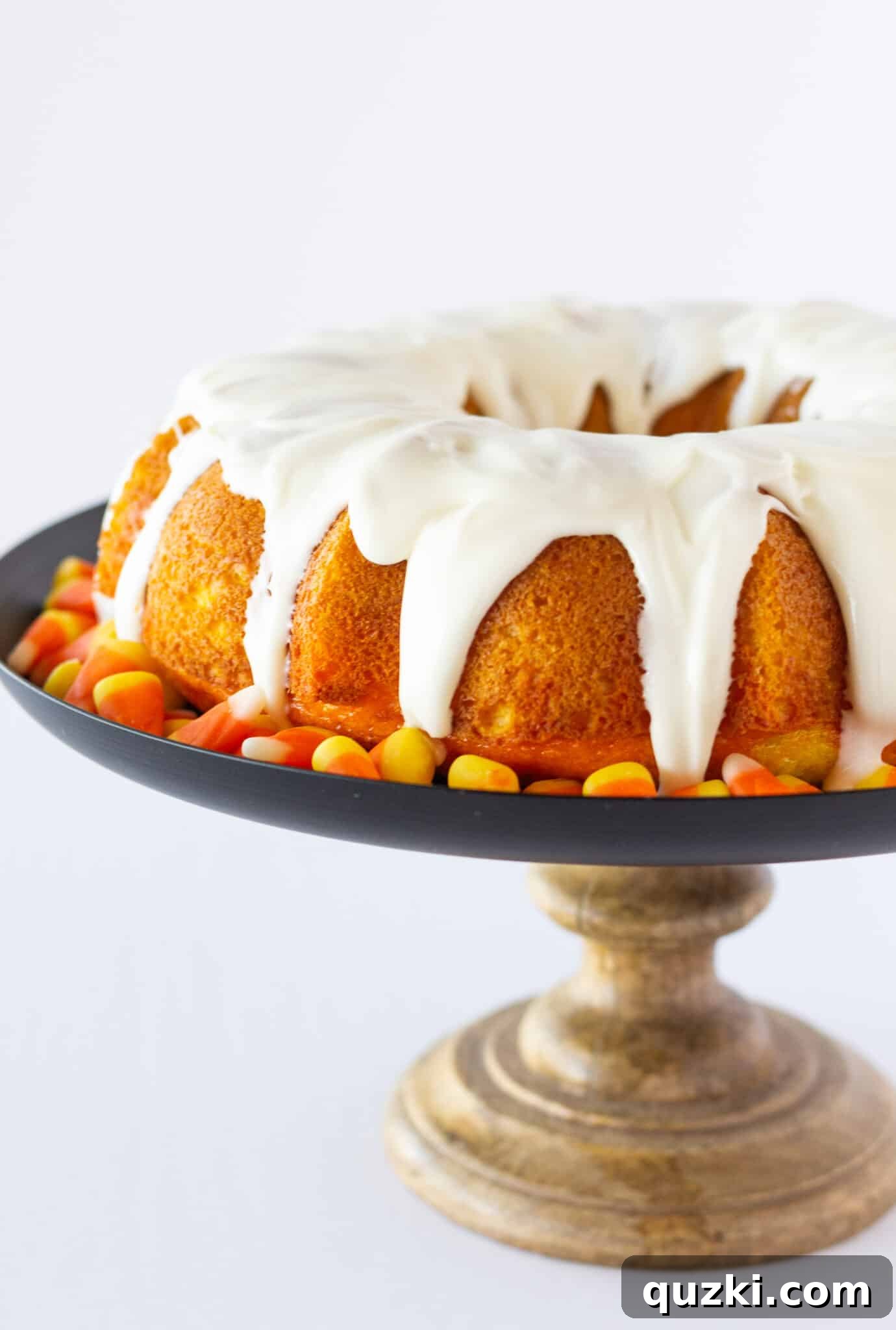 A beautifully glazed Candy Corn Bundt Cake on a decorative cake plate, ready to be served.
