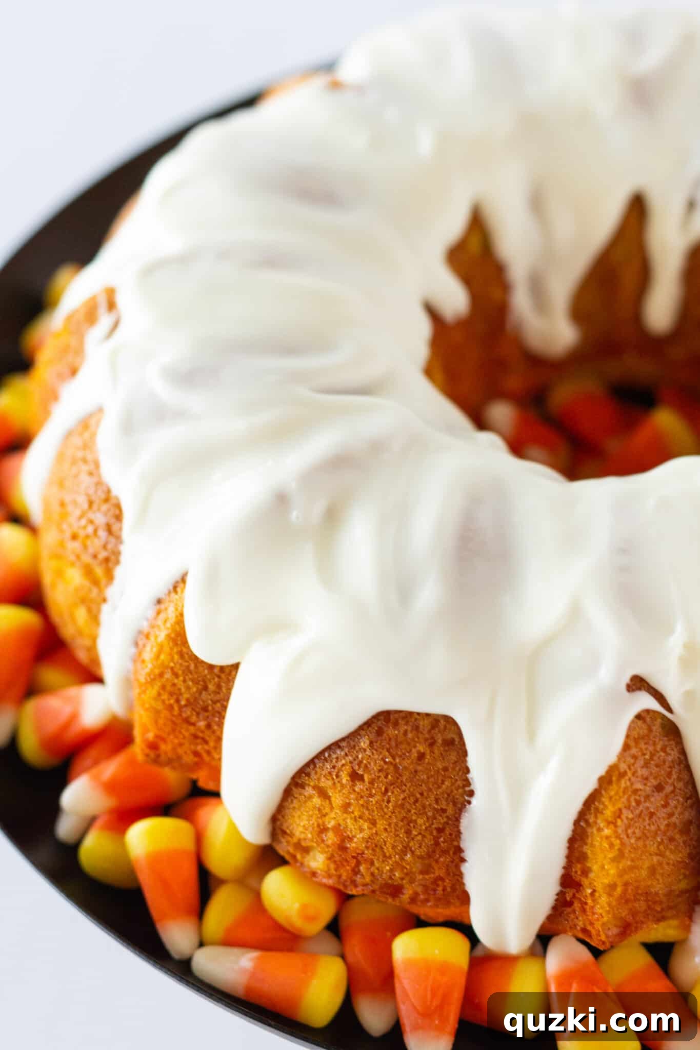 The finished Candy Corn Bundt Cake, generously coated with a smooth cream cheese glaze and adorned with candy corn candies.