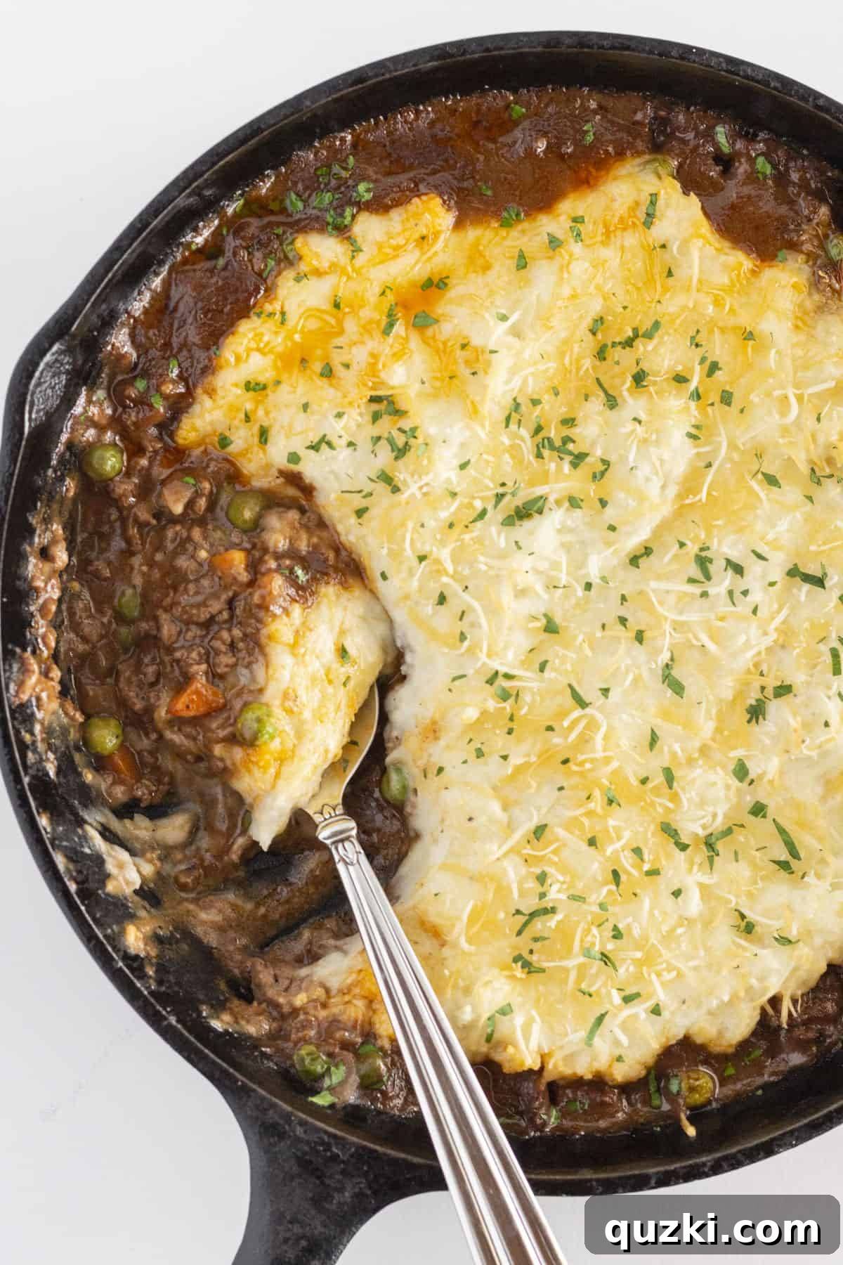 The finished shepherd's pie skillet in a cast iron skillet with a spoon, ready to be served.