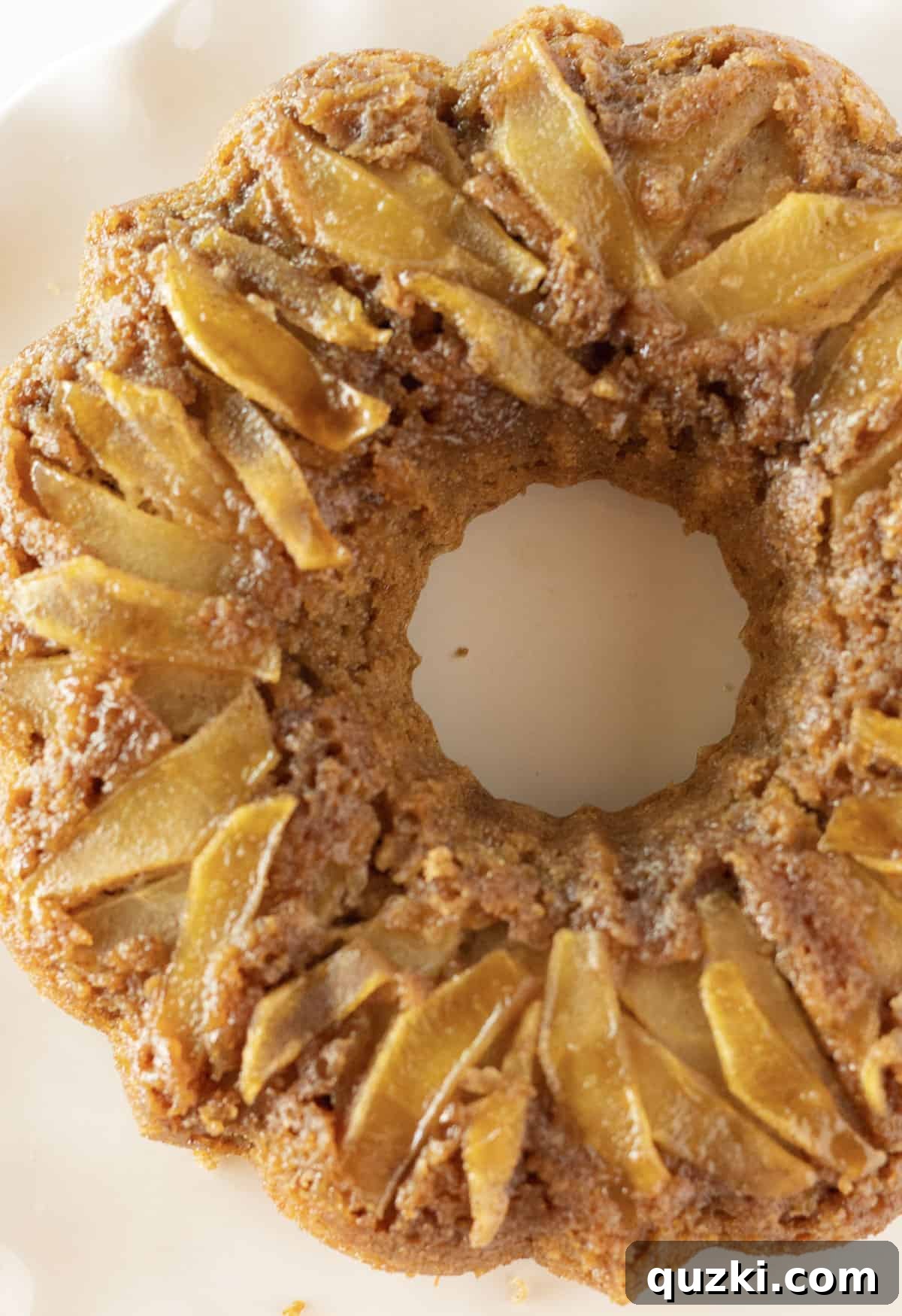 No-Fuss Caramel Apple Upside Down Cake 7 A beautifully presented whole Apple Upside Down Bundt Cake on a clean white serving plate, ready to be sliced.