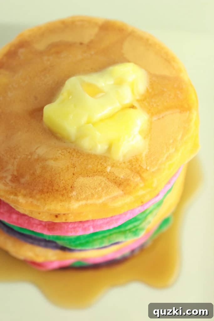 A stack of colorful, cooked rainbow pancakes ready to be served