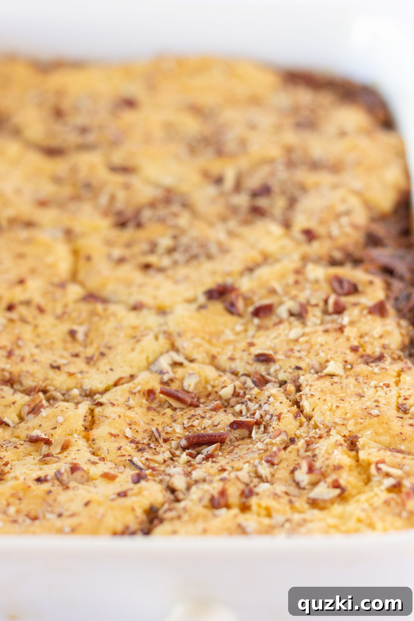 A generous serving of Easy Pecan Pie Cobbler with a Cake Mix, topped with vanilla ice cream, ideal for a sweet craving.