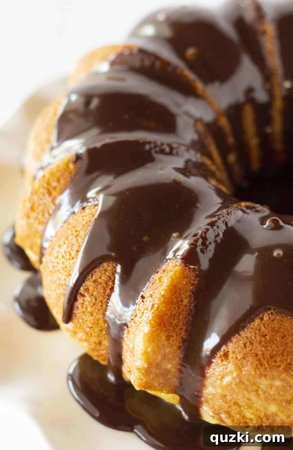 Effortless Boston Cream Pie Poke Cake 2 Looking at a Boston Cream Pie Poke Cake with Chocolate Ganache, showcasing its elegant bundt shape and shiny chocolate topping.