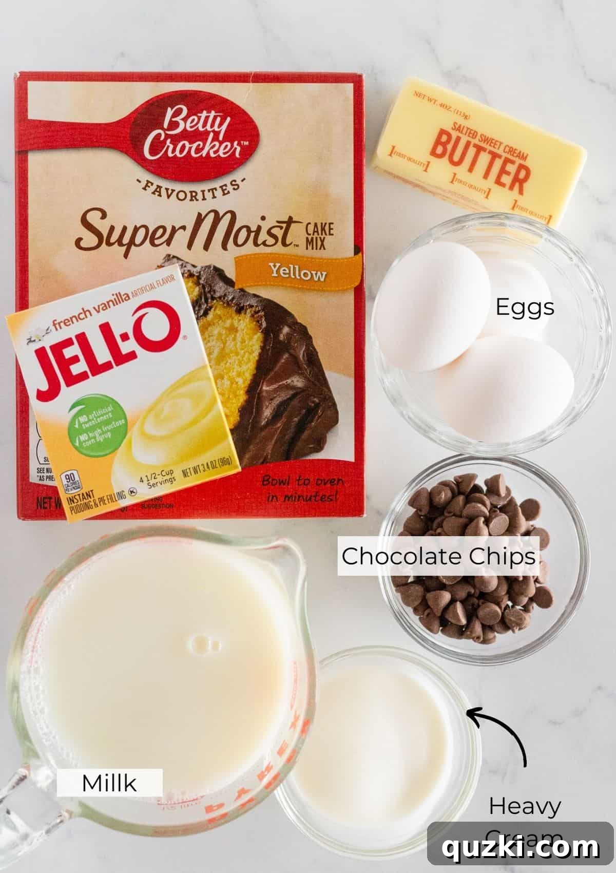 Effortless Boston Cream Pie Poke Cake 3 The array of essential ingredients meticulously laid out to prepare a luscious Boston Cream Pie Poke Cake, including cake mix, butter, eggs, milk, pudding mix, chocolate chips, and heavy cream.