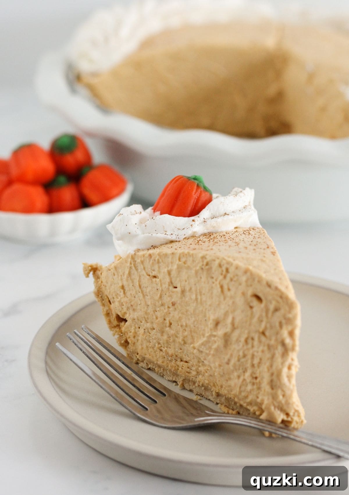 Perfect Homemade Pumpkin Spice 8 A delectable slice of pumpkin mousse pie on a plate, topped with generous whipped cream.