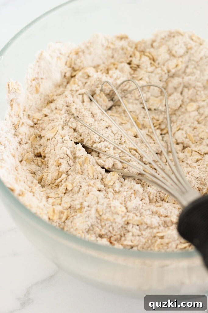 Whisking the dry ingredients together in a large mixing bowl for cake mix oatmeal cookies.