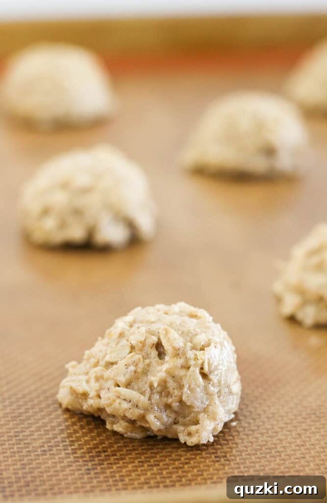 Scooping portions of cake mix oatmeal cookie dough onto a prepared baking tray.