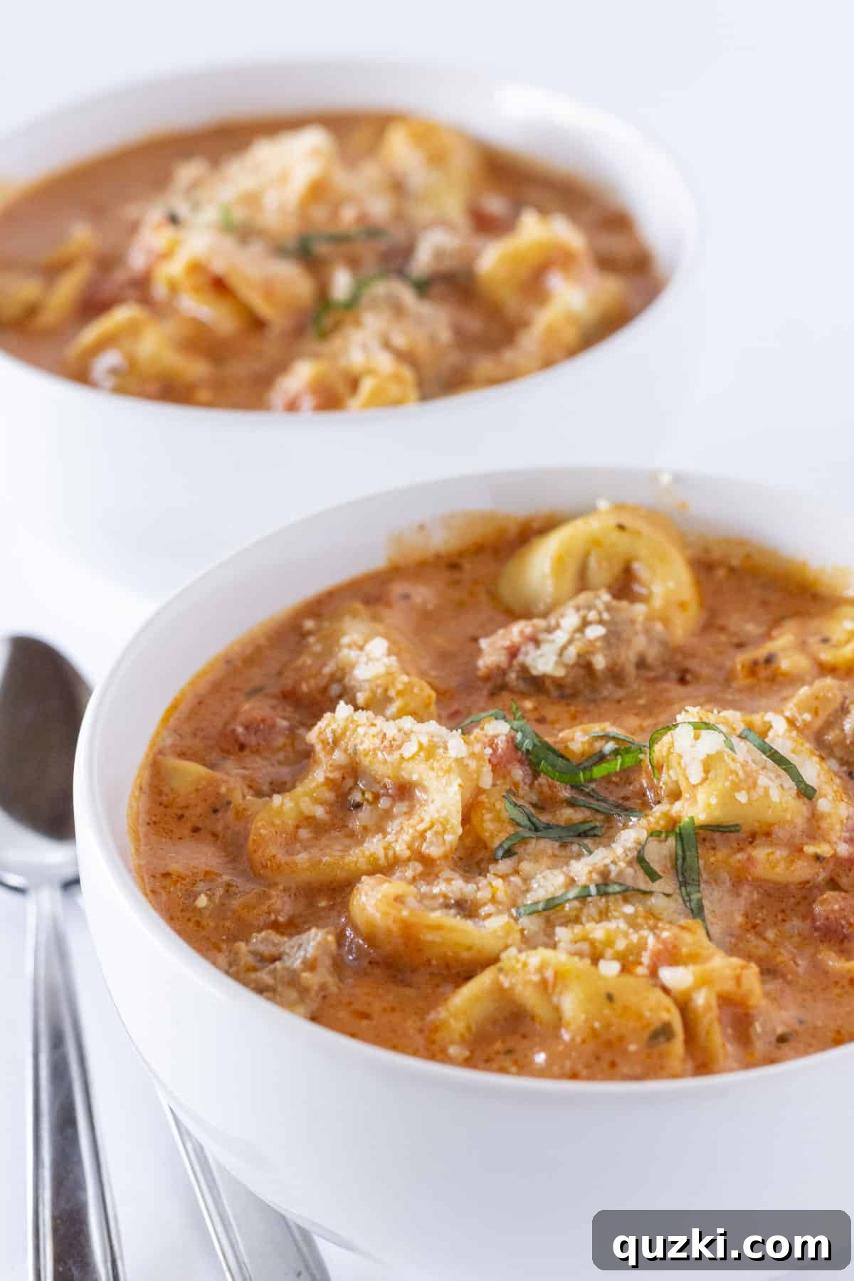 Cozy Slow Cooker Creamy Sausage Tortellini Soup 2 Two bowls of Crock Pot Sausage Tortellini Soup with parmesan and basil.