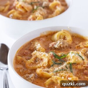 Two bowls of Tortellini Sausage Soup with parmesan and basil.