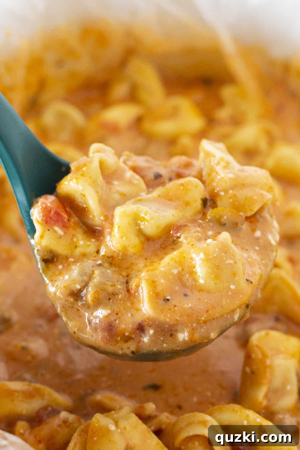 Cozy Slow Cooker Creamy Sausage Tortellini Soup 7 A scoop of tortellini soup on a green ladel.