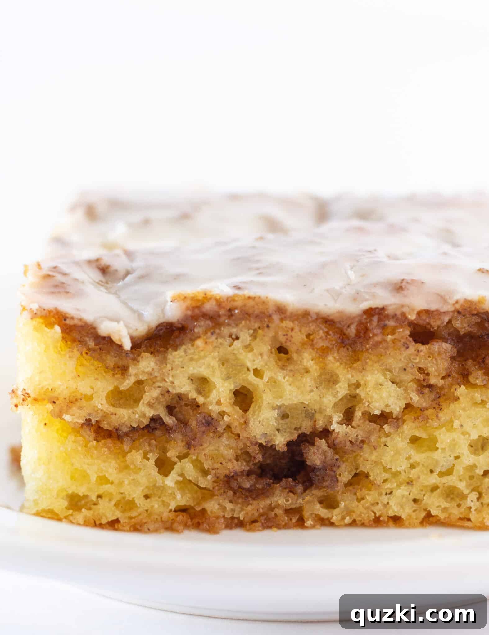 Effortless Cinnamon Roll Cake 2 A delectable slice of homemade cinnamon roll cake on a white plate, ready for serving.