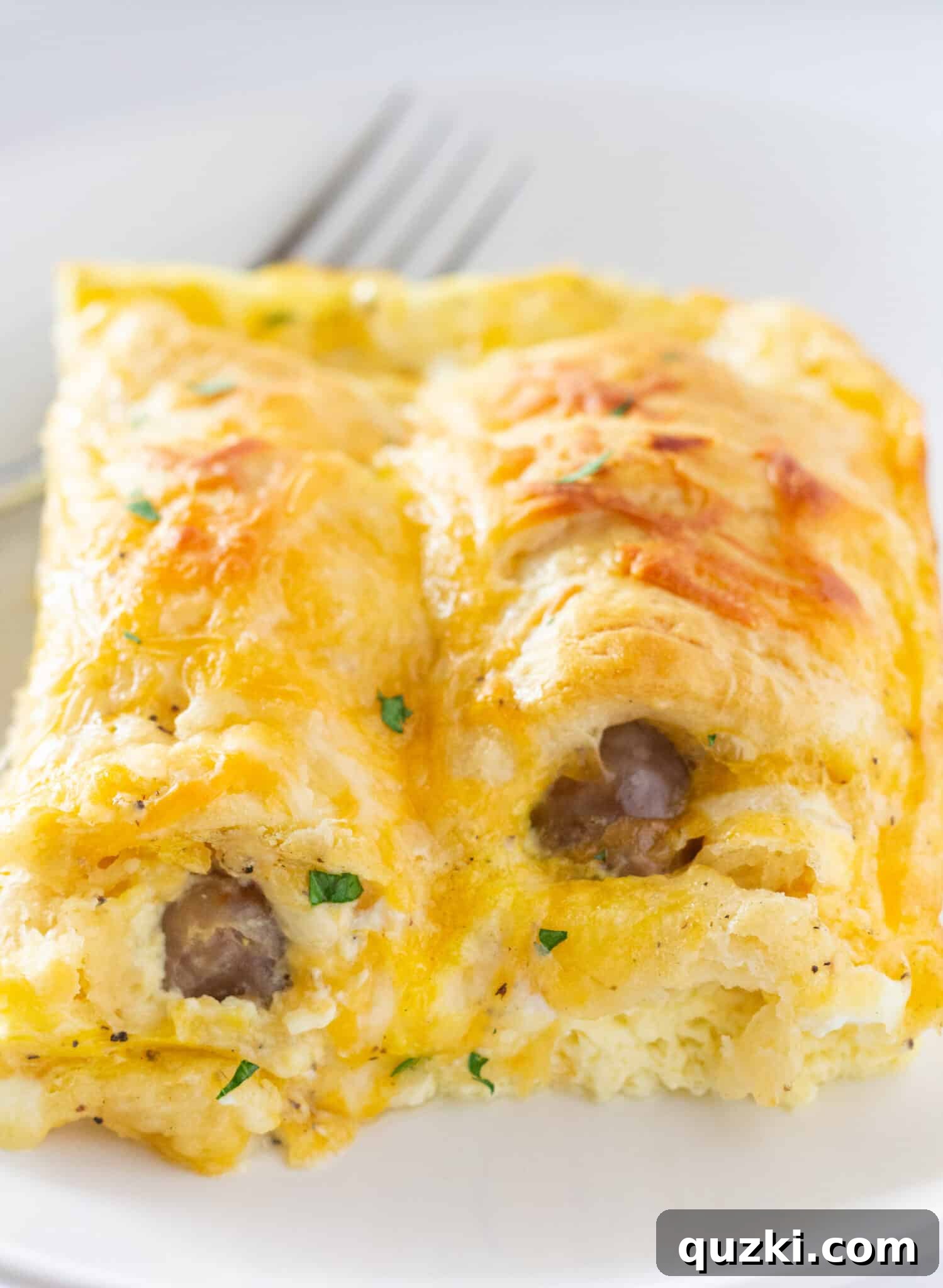Ultimate Pigs in a Blanket Breakfast Casserole 2 Golden brown Pigs in a Blanket Breakfast Casserole, freshly baked and ready to serve, featuring refrigerated crescent rolls and savory sausage.
