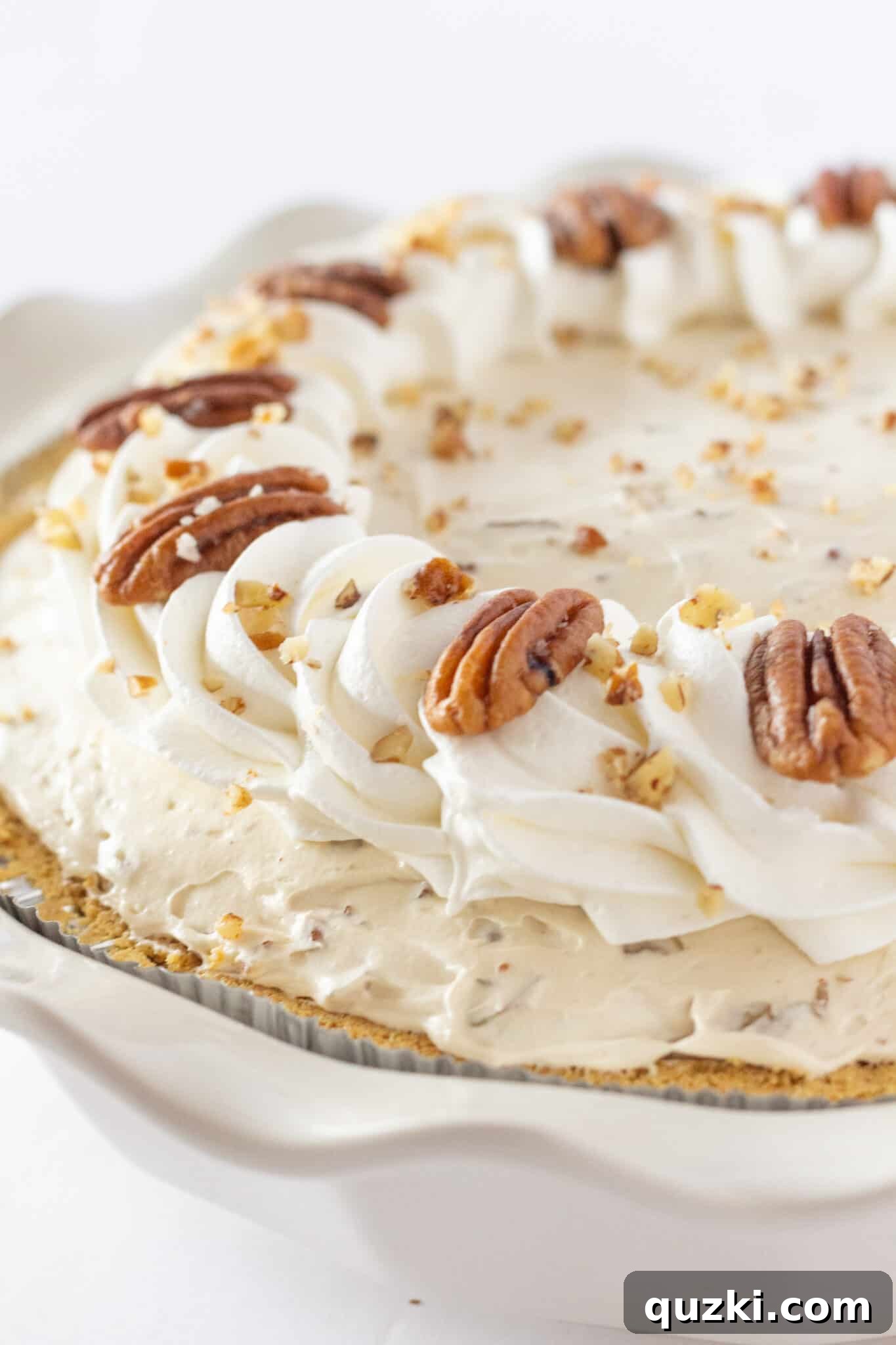 Thanksgiving's Easiest Butter Pecan Cream Pie with Cream Cheese 2 Easy Butter Pecan Cream Pie Recipe with Cream Cheese perfect for Thanksgiving, garnished with whipped topping and whole pecans.