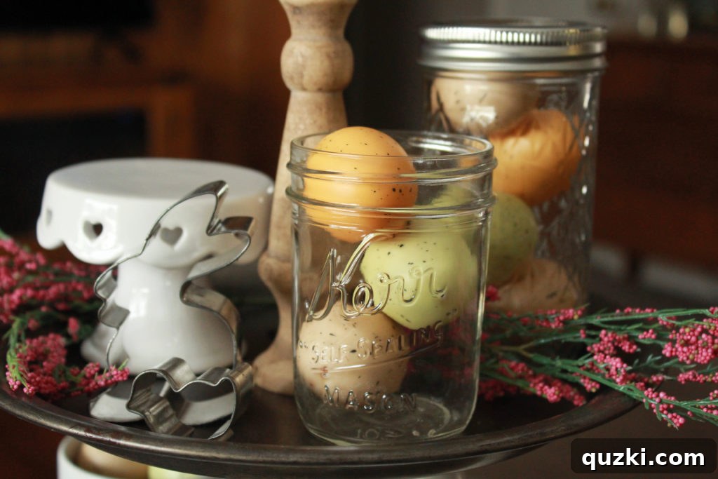 Hop into Easter Decor Ideas 3 Close-up of the top tier of an Easter tiered tray, featuring charming bunny and chick cookie cutters, speckled eggs nested in mason jars, and subtle faux pink flowers for a touch of color.