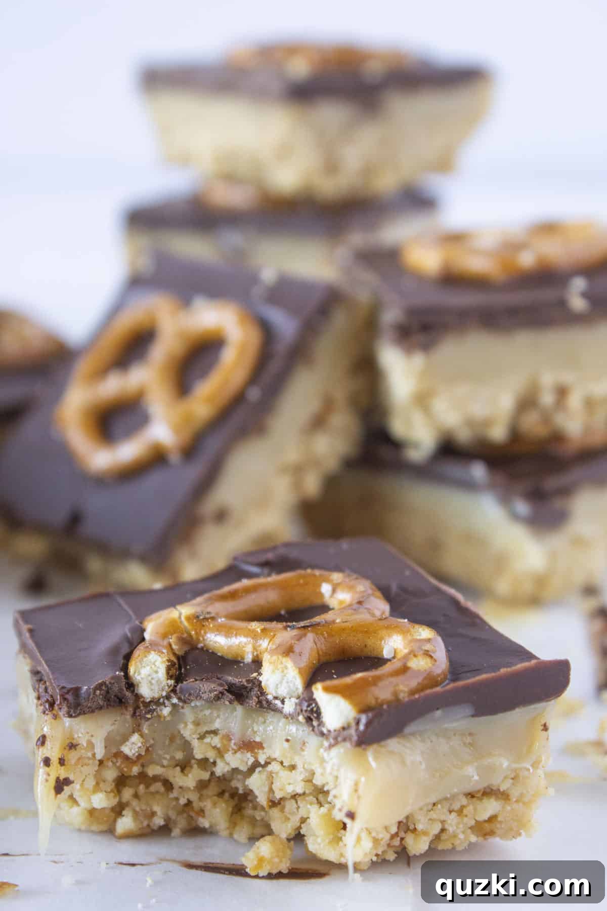 Decadent no-bake millionaire bars, featuring layers of shortbread-style crust, rich caramel, and chocolate topped with crunchy pretzels, showcased on a festive platter.