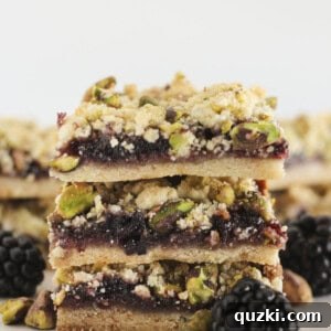 Three Blackberry Crumble bars stacked on each other with pistachios.