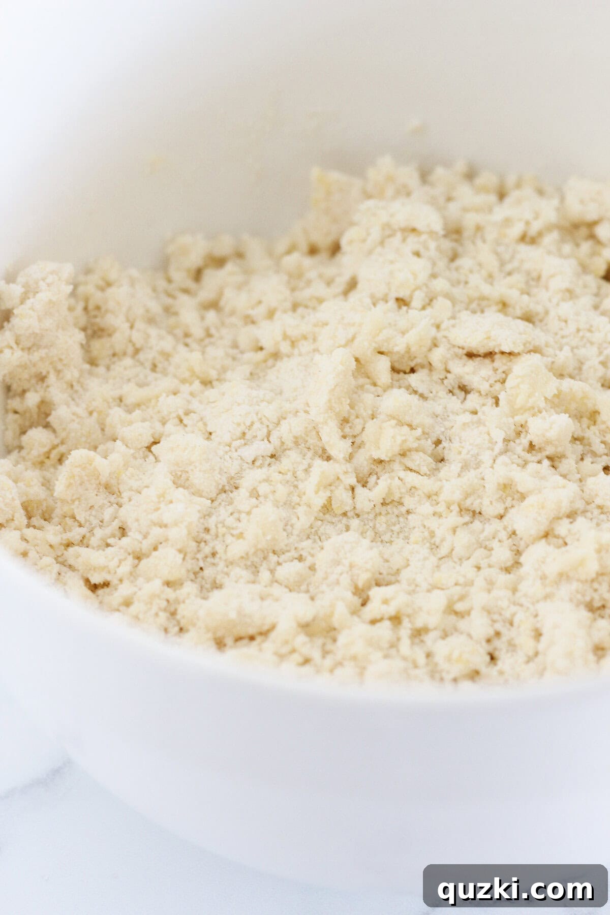 A close-up of the crumbly shortbread mixture made with cake mix, butter, and egg in a large mixing bowl, illustrating the desired texture before pressing into the pan.