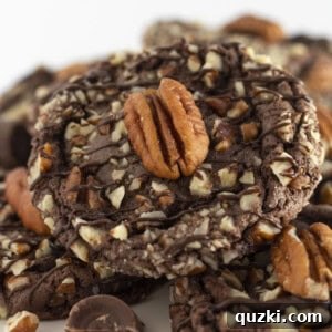 Turtle Cookies on a white cake plate with pecans and caramel.