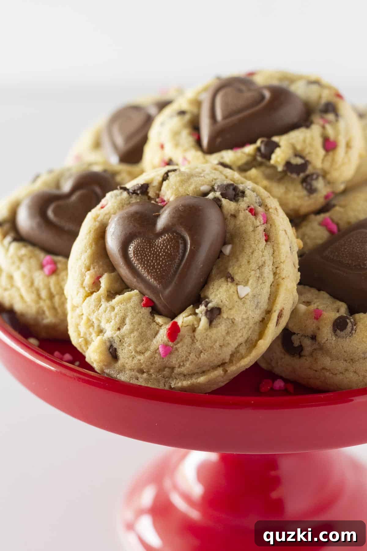 Sweetheart Chocolate Chip Cookies 7 A stack of Valentine's Chocolate Chip Cookies presented on a charming red cake plate, ready to be enjoyed.