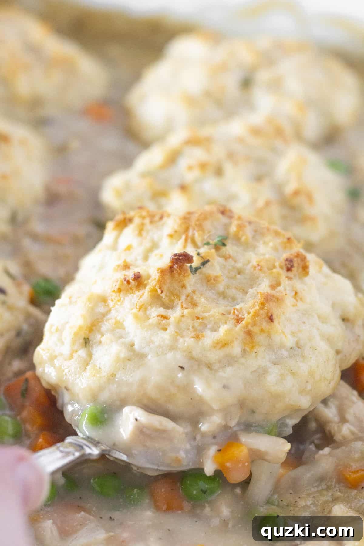 A generous serving of Easy Chicken and Biscuits Casserole being scooped from a baking dish.