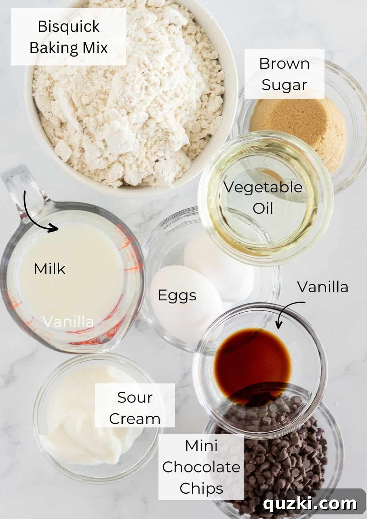 All the necessary ingredients laid out on a wooden surface for making pancake mix chocolate chip muffins, including a bowl of pancake mix, brown sugar, milk, eggs, vegetable oil, vanilla extract, sour cream, and a bowl of mini chocolate chips.