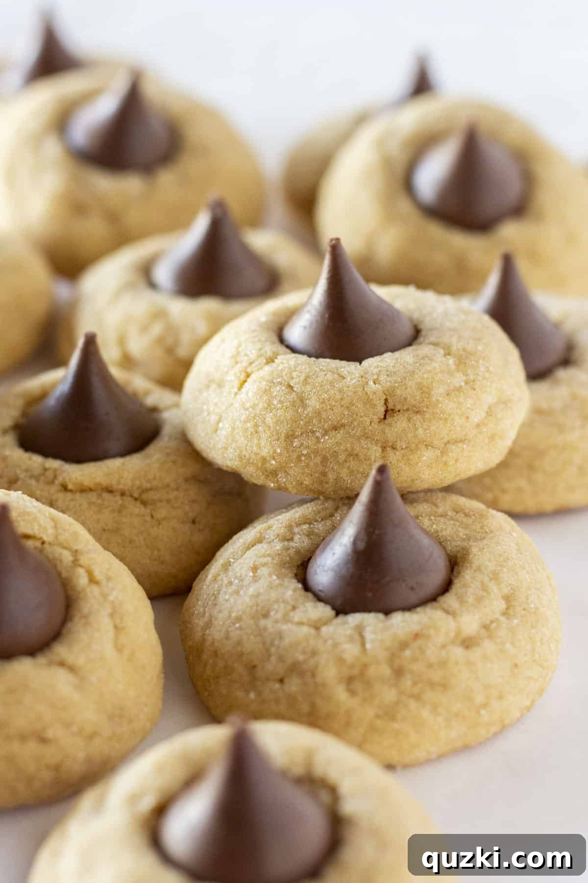 A tray full of golden-brown peanut butter blossom cookies, each topped with a melted Hershey's Kiss, showcasing their perfect shape and texture.